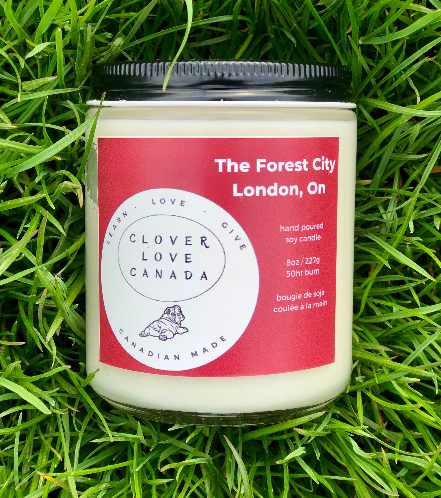 8 oz candle in grass with red label The Forest City London  On